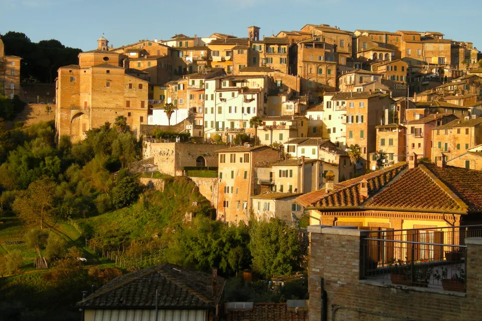 The city of Siena in Italy, located on a hillside and bathed in Tuscan sunlight.